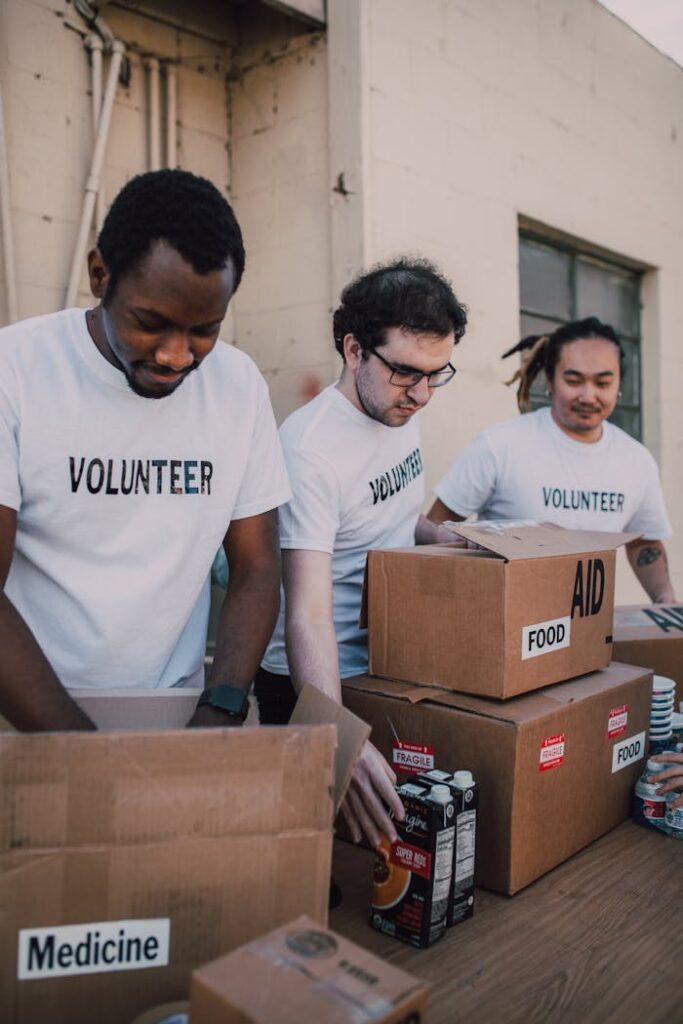 Group of volunteers preparing food and medicine boxes for charity distribution.