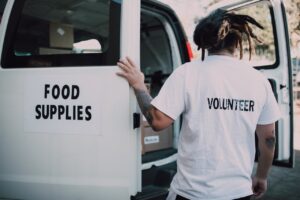 A volunteer loads food supplies into a van, showcasing charity and community support.