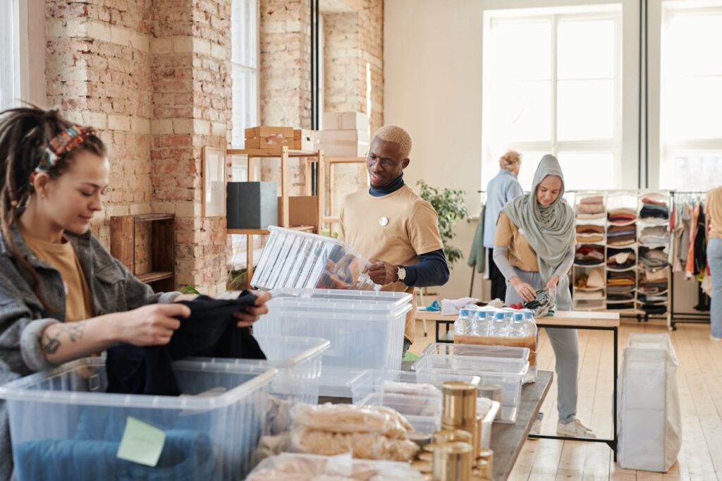 Group of diverse volunteers organizing donated clothing and supplies in a bright, airy warehouse.